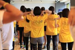 Group of L'OCCITANE employees with a yellow t-shirt with the Race for Vision Logo doing warm-ups before racing